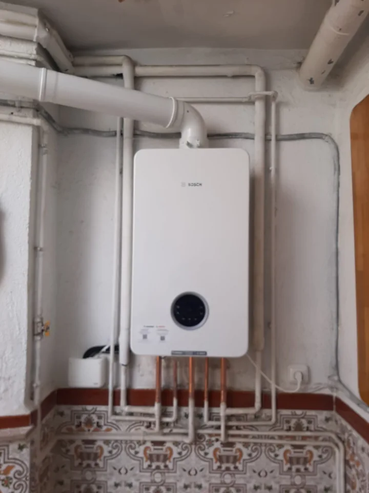 Equipo de agua caliente en una pared, con sus conexiones visibles